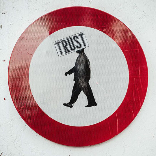Durchfahrt verboten mit Person in der Mitte. Auf dem Kopf klebt ein Sticker mit "Trust".